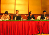 Speakers on the podium (Qingdao). From left: Interpreter Zhao, Chief Fellow Izumi Harada, Director Associate Mingjie Yang, and Special Assistant to the President Guoxiong Xu